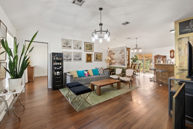 living room featuring dark wood-type flooring, a chandelier, and vaulted ceiling