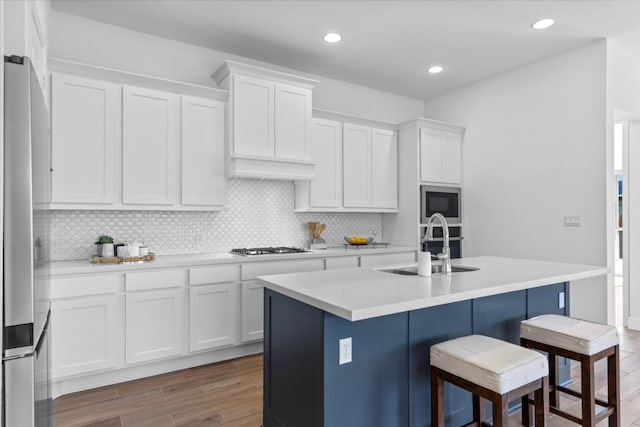 kitchen featuring white cabinetry, light hardwood / wood-style flooring, and a center island with sink