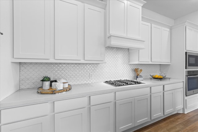 kitchen with dark hardwood / wood-style flooring, tasteful backsplash, white cabinetry, and stainless steel appliances