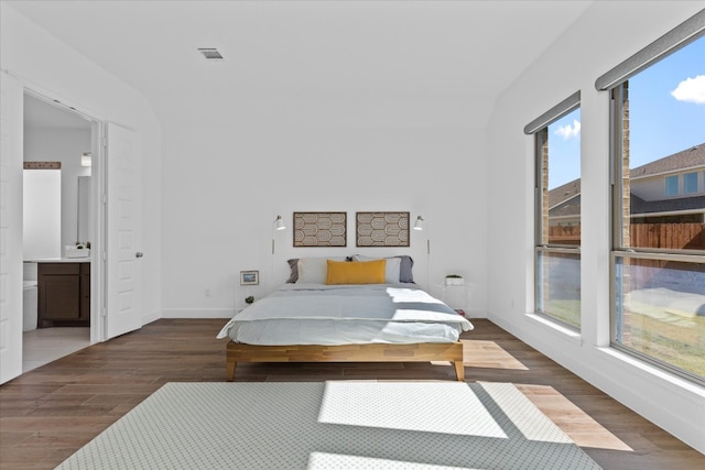 bedroom featuring ensuite bathroom and dark hardwood / wood-style flooring