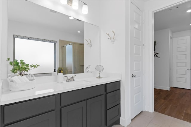 bathroom with wood-type flooring, vanity, and a shower with shower door