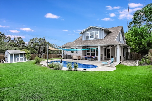 rear view of house featuring a patio area, a fenced in pool, a yard, and an outbuilding