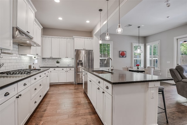 kitchen with a breakfast bar, a kitchen island with sink, dark wood-type flooring, white cabinets, and sink