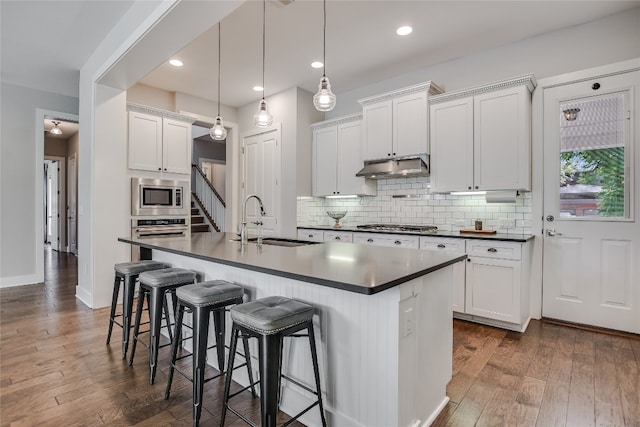 kitchen with dark wood-type flooring, sink, white cabinets, and an island with sink