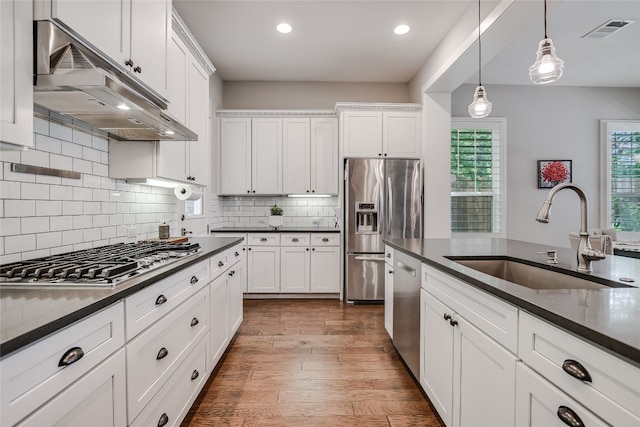 2717 Geraghty Ave, Austin, TX 78757 - kitchen with under cabinet range hood, appliances with stainless steel finishes, a sink, dark countertops, and recessed lighting
