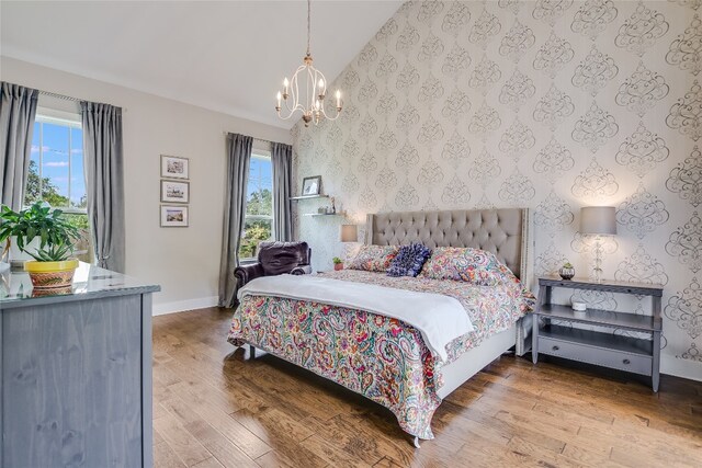 bedroom with an inviting chandelier, vaulted ceiling, and hardwood / wood-style flooring