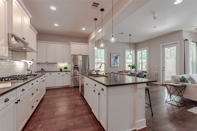 2717 Geraghty Ave, Austin, TX 78757 - kitchen with appliances with stainless steel finishes, dark countertops, dark wood-type flooring, under cabinet range hood, and recessed lighting