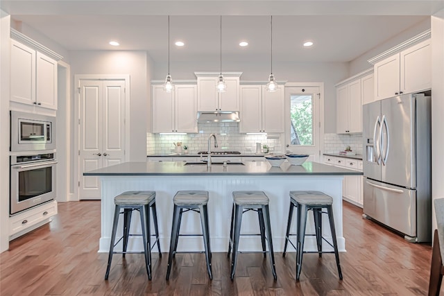2717 Geraghty Ave, Austin, TX 78757 - kitchen featuring appliances with stainless steel finishes, a kitchen breakfast bar, white cabinets, and recessed lighting