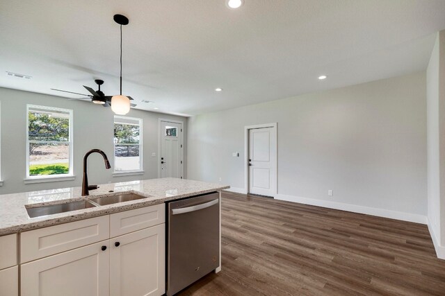 kitchen featuring dark wood-type flooring, white cabinets, sink, stainless steel dishwasher, and light stone countertops