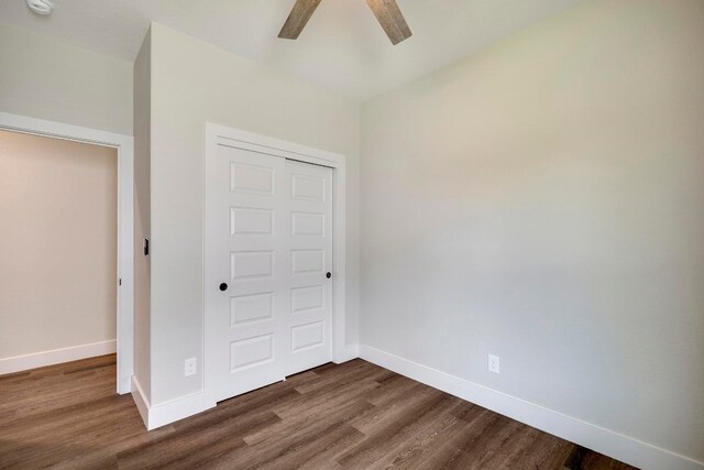 unfurnished bedroom with dark hardwood / wood-style floors, ceiling fan, and a closet