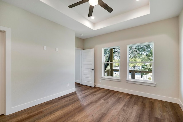 spare room featuring wood-type flooring, ceiling fan, and a raised ceiling