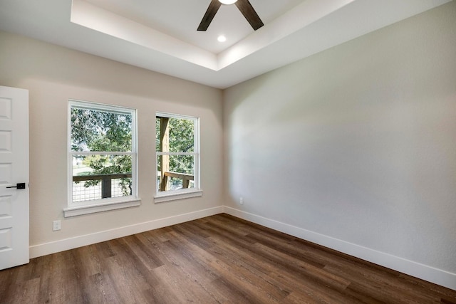 unfurnished room featuring ceiling fan, dark hardwood / wood-style floors, and a raised ceiling