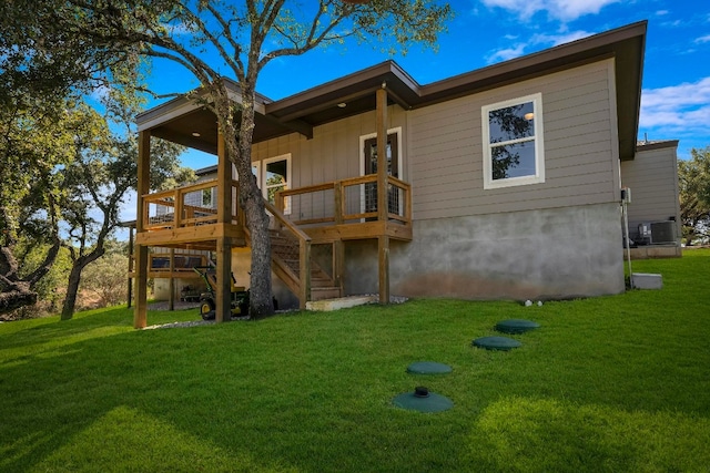 rear view of house featuring a wooden deck, a lawn, and cooling unit