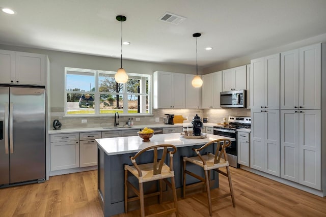 kitchen featuring sink, appliances with stainless steel finishes, a breakfast bar area, hanging light fixtures, and a center island