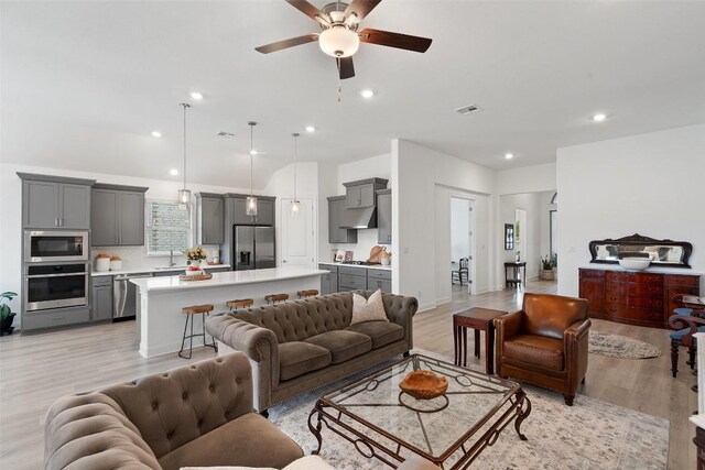 living room with ceiling fan, sink, and light hardwood / wood-style flooring