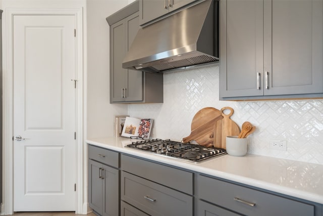 kitchen with gray cabinets, decorative backsplash, and stainless steel gas stovetop