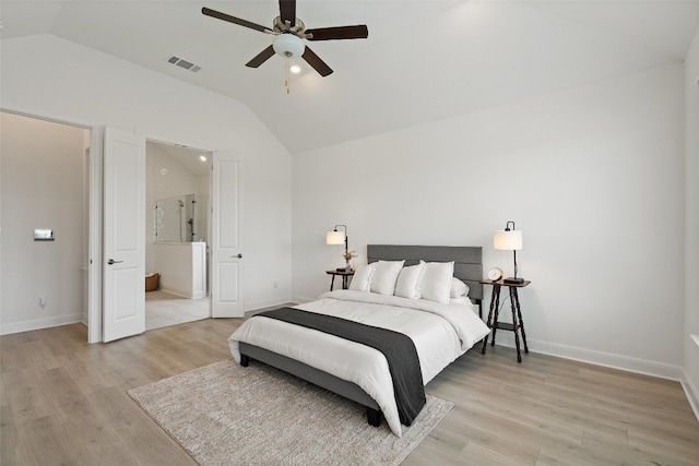 bedroom featuring ceiling fan, ensuite bath, light wood-type flooring, and vaulted ceiling