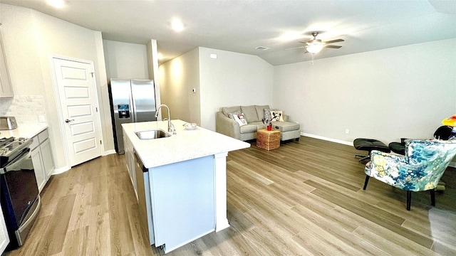 kitchen with decorative backsplash, appliances with stainless steel finishes, sink, white cabinets, and an island with sink