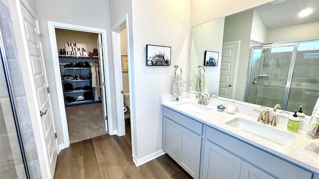 bathroom featuring wood-type flooring, vanity, toilet, and a shower with door