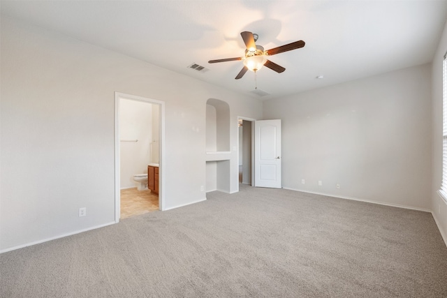 unfurnished bedroom with connected bathroom, light carpet, and ceiling fan