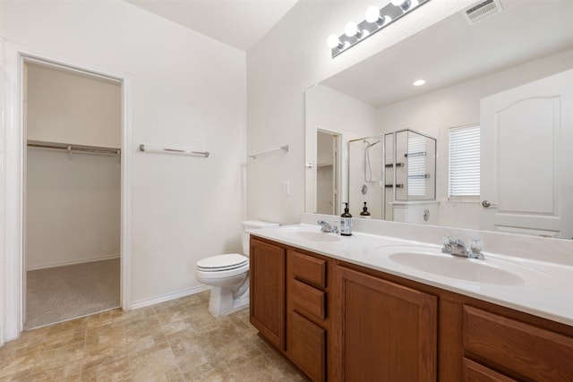 bathroom featuring toilet, vanity, and a shower with shower door