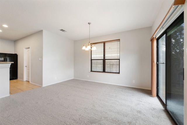 interior space with light colored carpet, decorative light fixtures, black refrigerator, and a notable chandelier