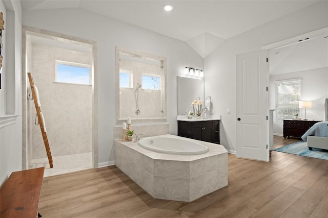 bathroom with hardwood / wood-style flooring, vanity, shower with separate bathtub, and vaulted ceiling