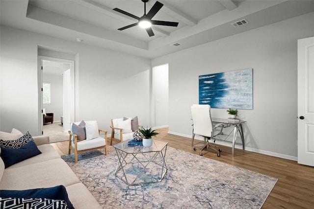 living room featuring beamed ceiling, hardwood / wood-style flooring, a raised ceiling, and ceiling fan