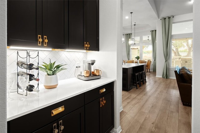 bar with backsplash, pendant lighting, and light hardwood / wood-style floors