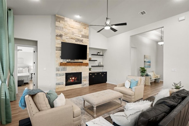 living room featuring a stone fireplace, ceiling fan, high vaulted ceiling, and wood-type flooring