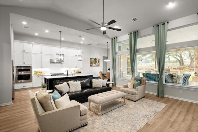 living room featuring ceiling fan, light wood-type flooring, and lofted ceiling