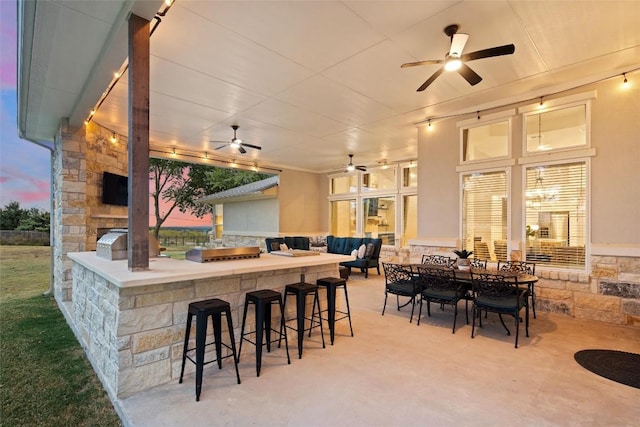 patio terrace at dusk featuring area for grilling and an outdoor bar