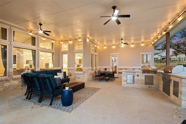 patio terrace at dusk with an outdoor living space, an outdoor kitchen, and area for grilling