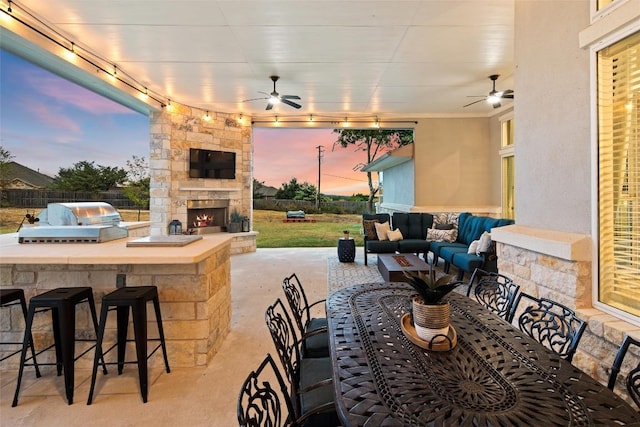 view of patio / terrace featuring an outdoor living space with a fireplace, ceiling fan, exterior bar, and exterior kitchen