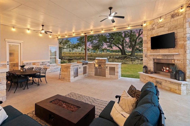 view of patio with a grill, ceiling fan, an outdoor kitchen, and an outdoor stone fireplace