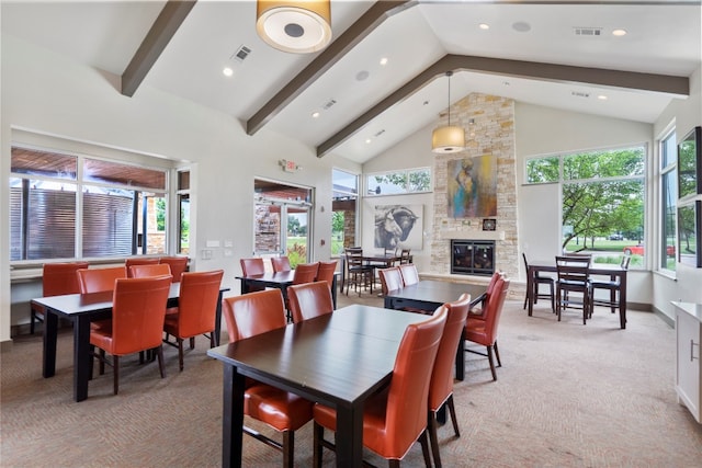 carpeted dining area with high vaulted ceiling, beam ceiling, and a stone fireplace