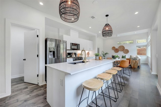 kitchen with black appliances, a kitchen island with sink, white cabinetry, sink, and light hardwood / wood-style flooring