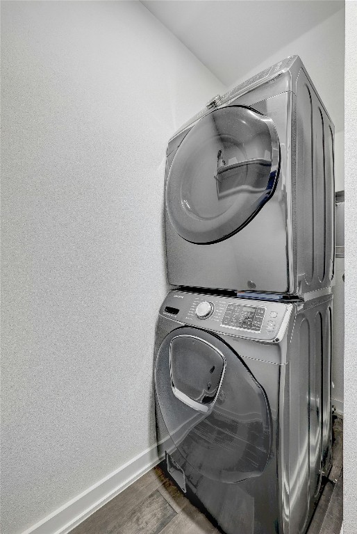 laundry room featuring dark hardwood / wood-style floors and stacked washer and clothes dryer