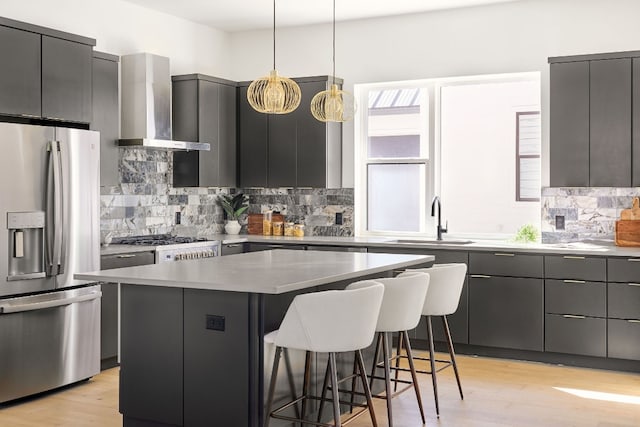 kitchen with stainless steel appliances, a center island, sink, wall chimney range hood, and a breakfast bar