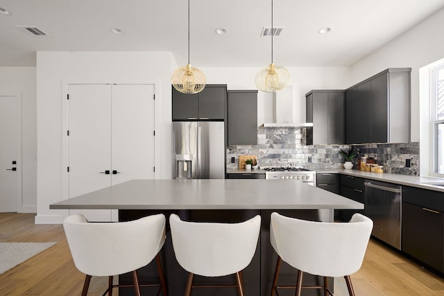 kitchen with a center island, light hardwood / wood-style flooring, hanging light fixtures, gray cabinetry, and appliances with stainless steel finishes