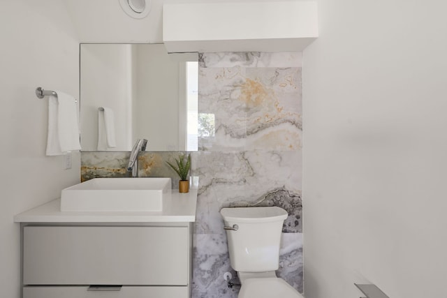 bathroom with toilet, vanity, and tile walls