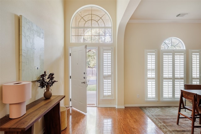 entryway with light wood-type flooring, a wealth of natural light, and crown molding