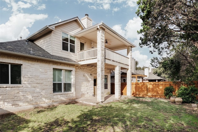 back of house featuring a lawn, a balcony, and a patio