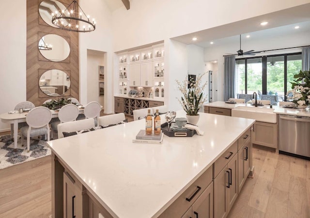 kitchen with pendant lighting, light wood-type flooring, stainless steel dishwasher, and a large island