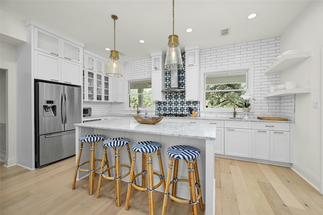 kitchen featuring stainless steel appliances, light hardwood / wood-style floors, white cabinets, and a kitchen island