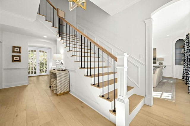 staircase featuring ornate columns, hardwood / wood-style floors, french doors, and crown molding