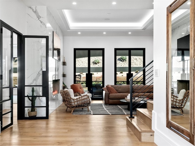 living room featuring a raised ceiling and light wood-type flooring