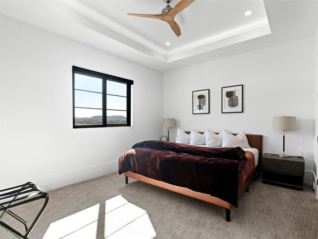 carpeted bedroom featuring a tray ceiling and ceiling fan