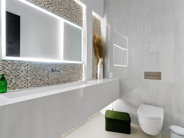 bathroom featuring tasteful backsplash, toilet, and tile walls