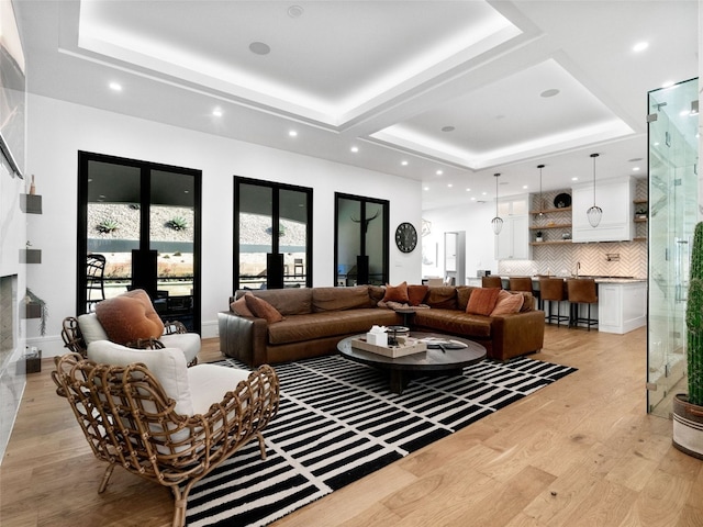 living room with french doors, a tray ceiling, and light hardwood / wood-style flooring